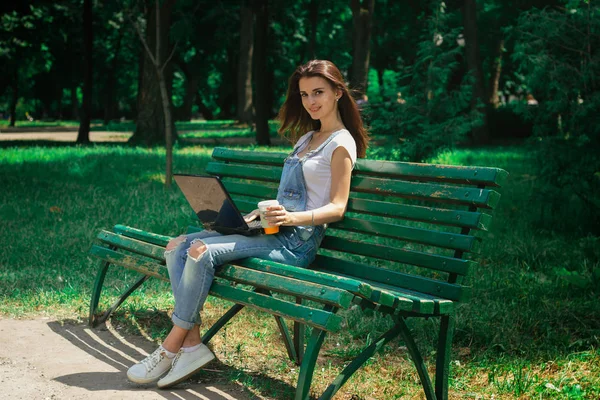 ベンチに座っての手にノート パソコンで魅力的な女の子 — ストック写真