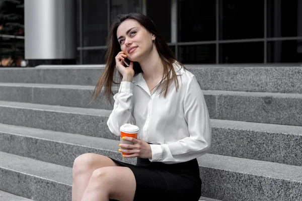 beautiful Office Lady says on the phone smiles and drinks coffee