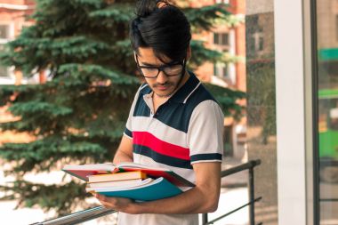 ellerinde kitaplarla çok esmer öğrenci bir gözlük takar