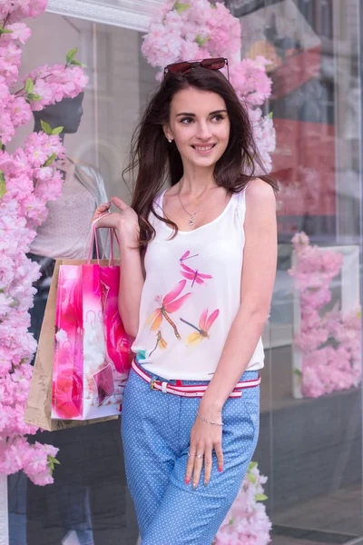Joven hermosa chica sonríe después de comprar con bolsas en las manos —  Fotos de Stock