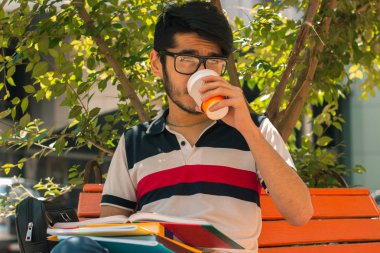 güzel göz alıcı adam kahve içer ve bir kitap tutar