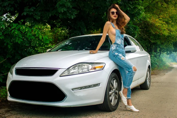 Привлекательная девушка в сексуальном наряде позирует возле белого автомобиля — стоковое фото