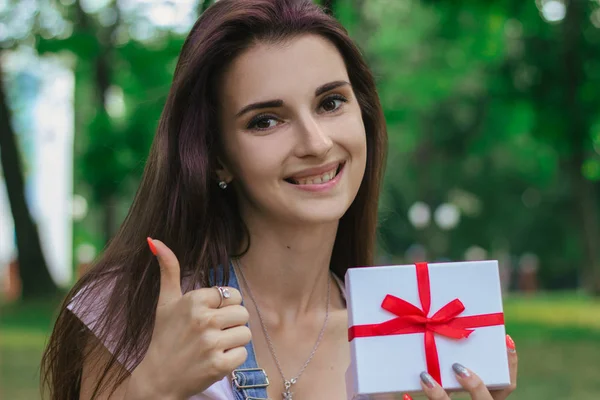 En närbild porträtt av ung vacker flicka som håller en gåva i hand, ler — Stockfoto
