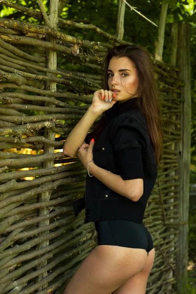 Beautiful sensual girl in black body poses near a wooden wall — Stock Photo, Image