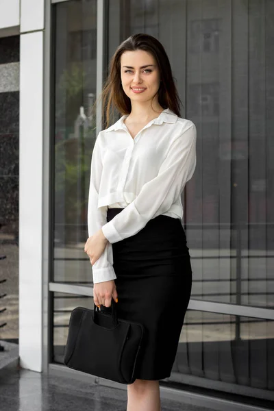 Ritratto verticale di affascinante donna d'affari con borsa in mano guardando e sorridendo sulla macchina fotografica — Foto Stock