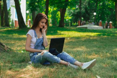 cep telefonu konuşurken ve bir lapt kullanarak genç güzel esmer kız