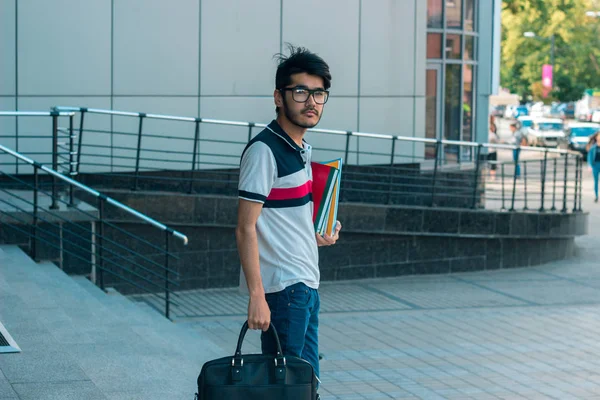 Ung brunett student pojke med väska och böcker i händerna — Stockfoto