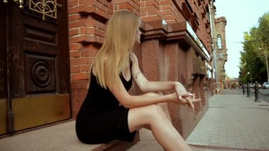 siyah bir elbise sokakta oturan çekici genç sarışın