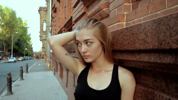 Mooie blonde staat op straat en rechtzetten van je haar — Stockvideo