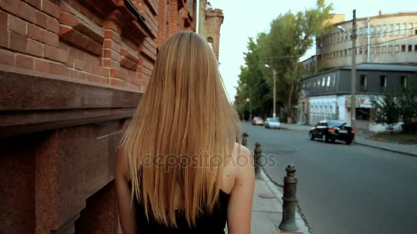 Delgada joven rubia camina por la ciudad — Vídeo de stock