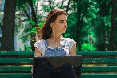 siyah bir dizüstü bilgisayar ile bir bankta genç esmer