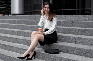 oturur gülümseyen ve telefonla konuşurken sevimli genç kız