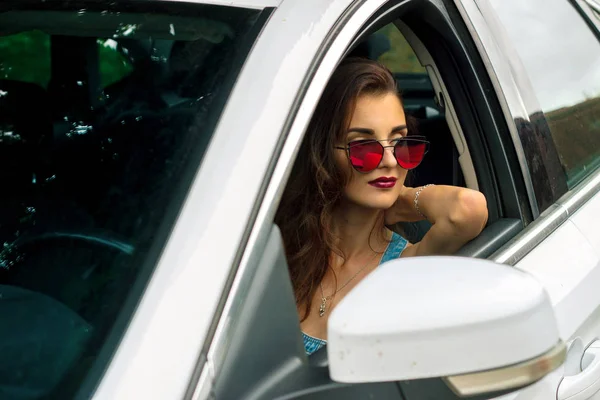 Ritratto di una giovane donna glamour con occhiali luminosi in macchina — Foto Stock