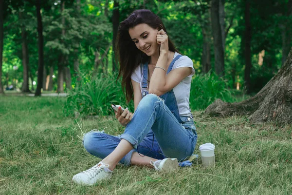 mutlu güzel kız çim gülümsüyor oturur ve müzik dinliyor