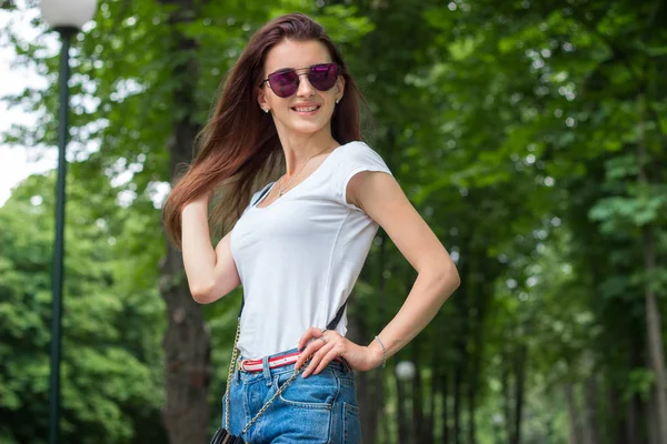 Bella signora sorridente in occhiali e pantaloncini si trova nel parco — Foto Stock