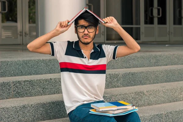 Grappige kerel op de straat zitten en houdt van een boek op je hoofd — Stockfoto