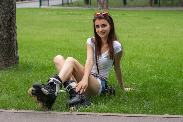 Glücklich schönes junges Mädchen sitzt auf dem Gras in Rollen — Stockfoto