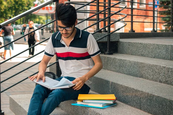 merdivenlerde oturan kitapları ile şık adam