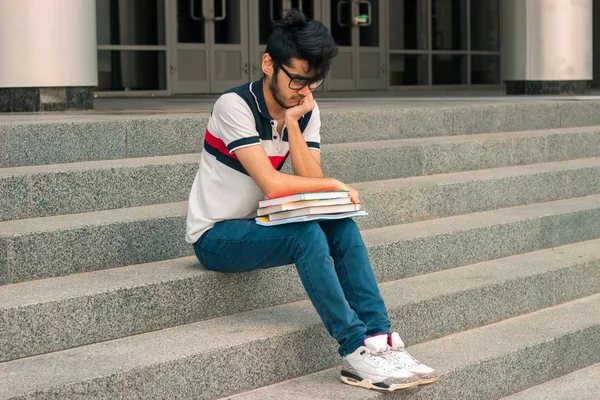 Genç öğrenci sokak ve bir kitap okuma oturur