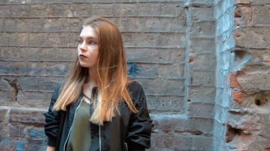 güzel sarışın bir taş duvar sokak ve kamera için poz yakınındaki standları