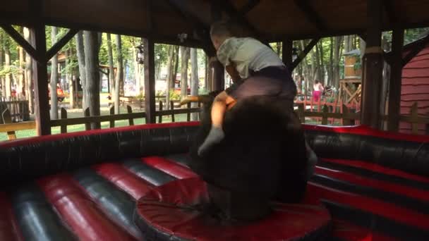 Хлопець їде на механічній їзді бика — стокове відео
