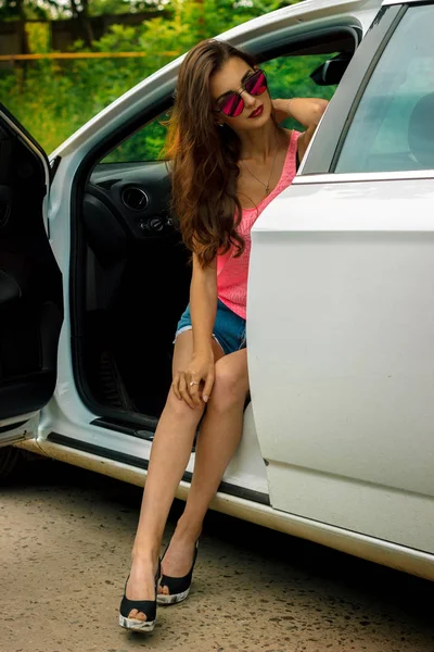 Вертикальный портрет модной девушки в очках, сидящей в машине — стоковое фото