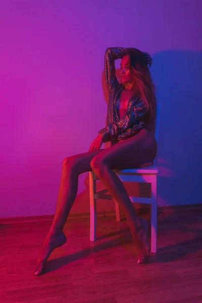 Sexy, ung, halvnaken kvinne i glitterjakke uten truse på stolen – stockfoto