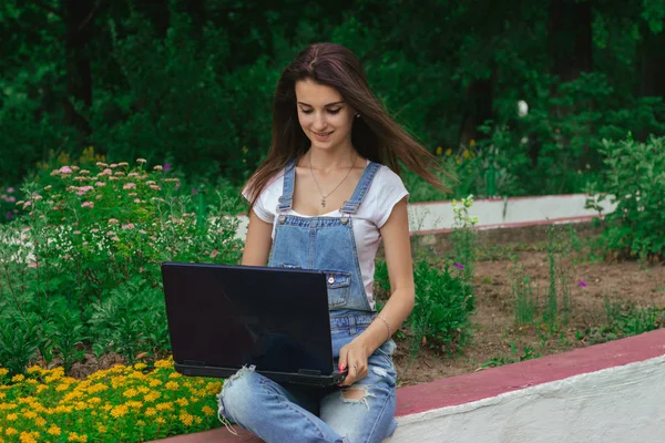 dizüstü bilgisayarınızda sokak parmak izlerinde bir çiçek parkta oturan güzel Bayan gülümseyen