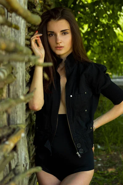 Bella ragazza gentile in pantaloncini neri e top sta vicino al muro — Foto Stock