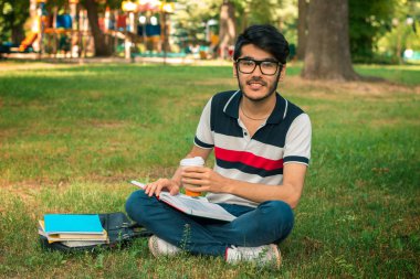 sevimli öğrenci yeşil çim ve kitap okumak üzerinde oturur