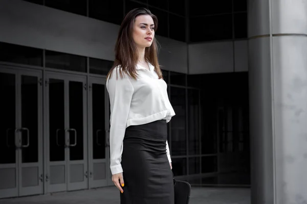 Ελκυστικό επιχειρηματικό κορίτσι στέκεται σε μια οδό σε ένα άσπρο πουκάμισο και μαύρη φούστα — Φωτογραφία Αρχείου