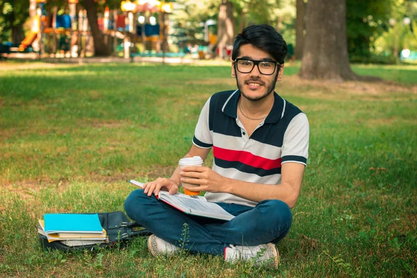 Uroczy student siedzi na zielonej trawie i czytanie książek — Zdjęcie stockowe