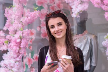 gülümseyen bir telefon ve bir bardak kahve ile büyüleyici kadın