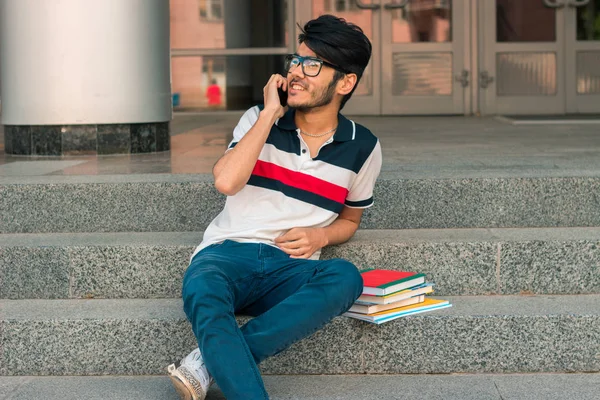 trendy çekici adam kitaplarla bir sokakta oturuyor