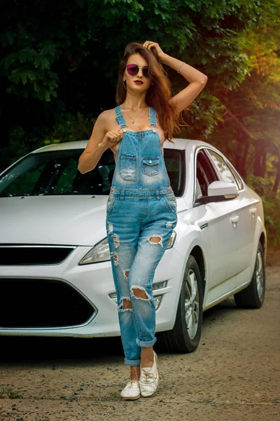 Knappe jonge dame met grote silicone tieten draagt een algehele jeans op naakte lichaam — Stockfoto