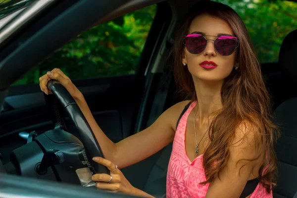 Joven hermosa morena se sienta junto al volante en un coche — Foto de Stock