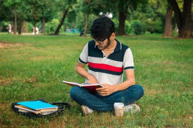 bir çim üzerinde kitap okuma esmer öğrenci adam