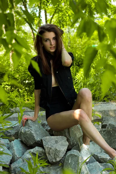 Krásná dívka v černých šatech pózuje na skalách — Stock fotografie