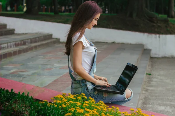 Una joven esbelta sentada con un portátil — Foto de Stock