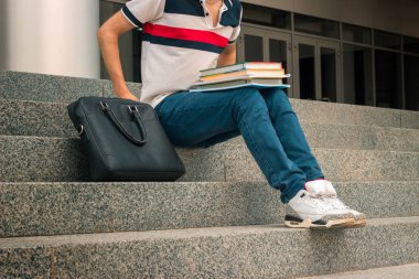 kot pantolon genç adam merdivenlerde oturur ve siyah çanta kendini