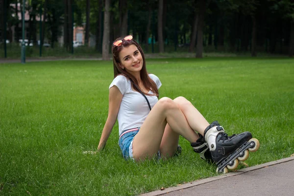 Cutie young girl with roller on her legs resting on a grass — Stock Photo, Image