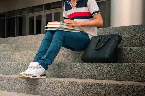 Nogi młody facet, który siedzi na schodach i czyta książki — Zdjęcie stockowe