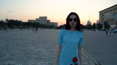 güzel moda esmer siyah gözlük ve mavi bir elbise gider kamerada akşam şehir