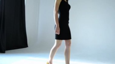 siyah elbiseli genç seksi esmer stüdyoya gider ve bir sandalyeye oturur