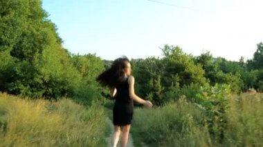 sokak ve kameraya bakarak aşağı siyah elbiseli esmer çalışır