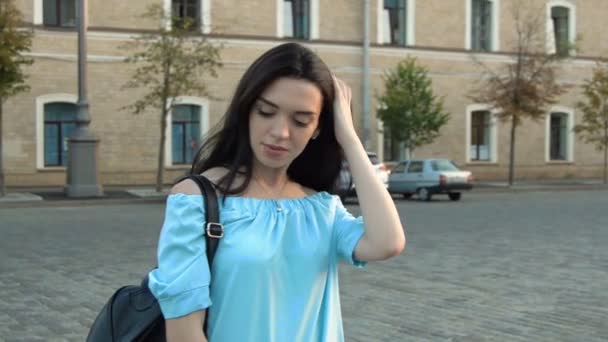 Affascinante bruna in camicetta blu si trova sulla strada e raddrizza i capelli — Video Stock