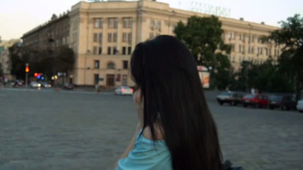 Jeune brune cheveux marchant dans la rue le soir et dit par téléphone — Video