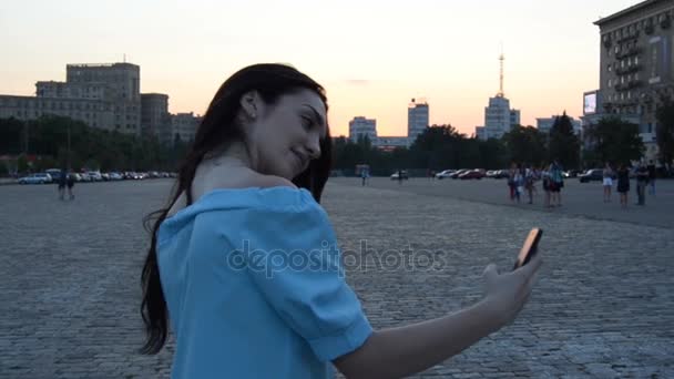 Charmiga brunett står på gatan leenden och gör foto på telefon — Stockvideo