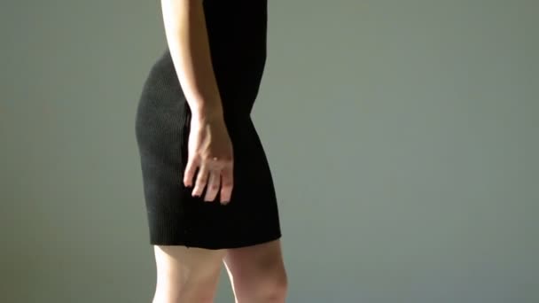 Νεαρό κορίτσι σε ένα μαύρο φόρεμα με σέξι γλουτούς περπατά σε Studio και κατέχει το χέρι καρέκλα — Αρχείο Βίντεο