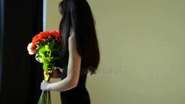 Mooie jonge brunette in zwarte jurk gaat naar de Studio en zet de bloemen in een vaas — Stockvideo